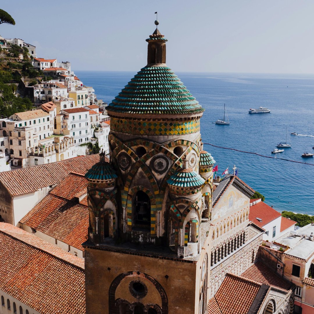 The 13th-century majolica-tiled bell tower of the Cathedral of Sant'Andrea in Amalfi, photographed from above with the sea behind